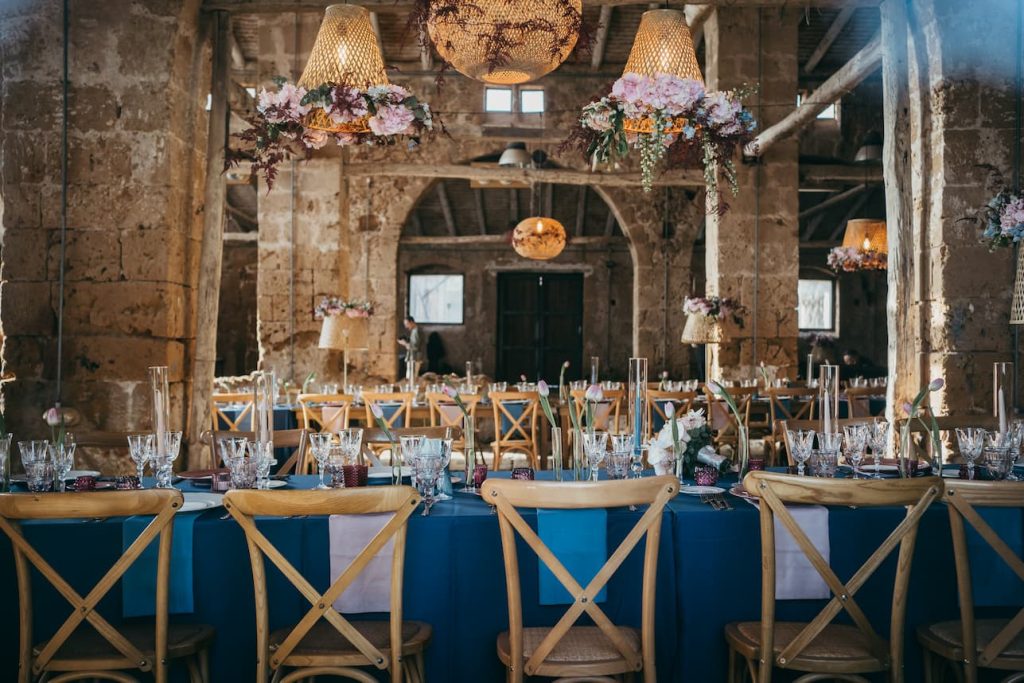 primo piano di tavolo con tovaglioli rosa e blu e tre lampadari a sospensione in rattan e fiori