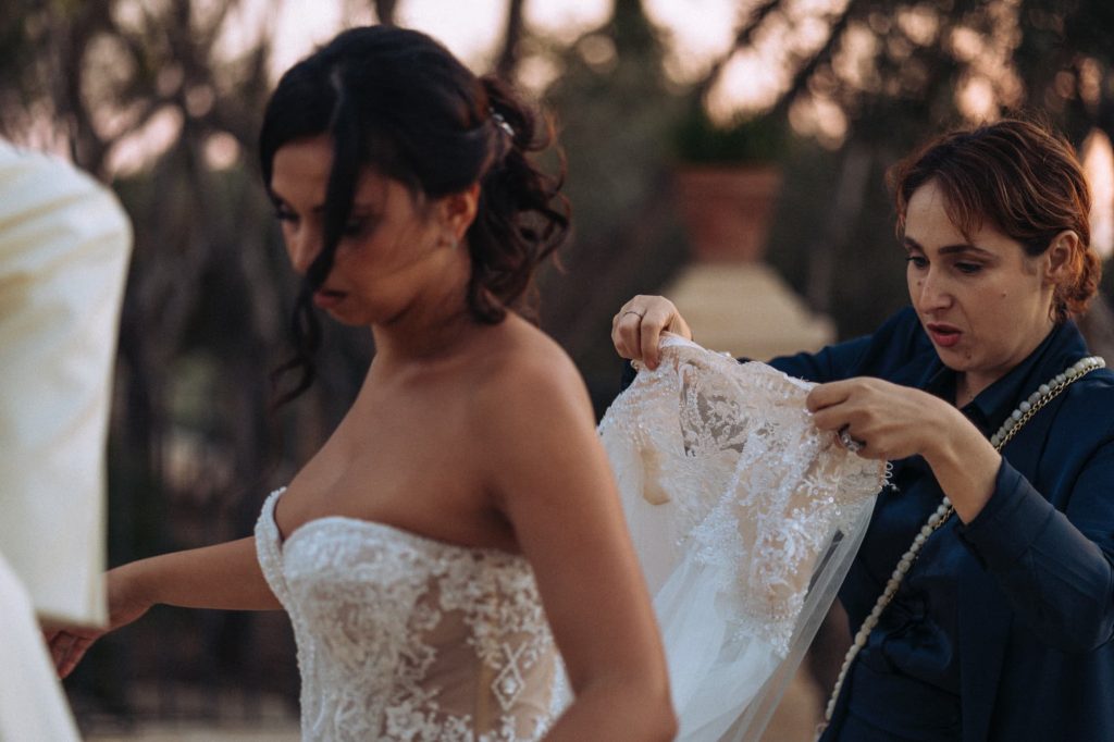 la sposa e francesca in giardino che sistemano l'abito