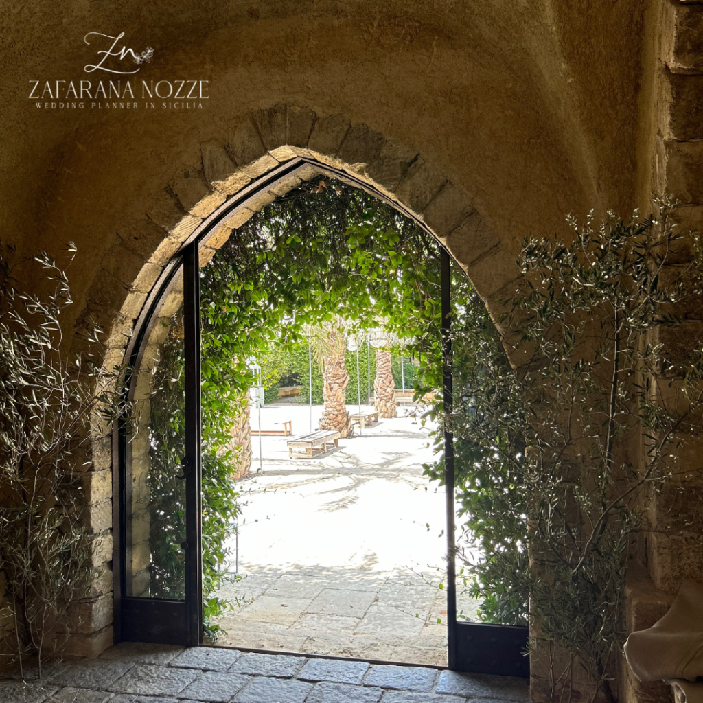 arco entrata giardino location sicilia alberi verdi e pavimento in pietra bianco