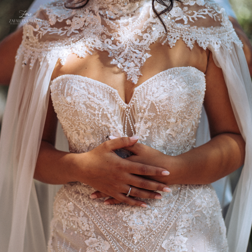 abito bianco da sposa in primo piano indossato dalla sposa con le mani giunte sul ventre