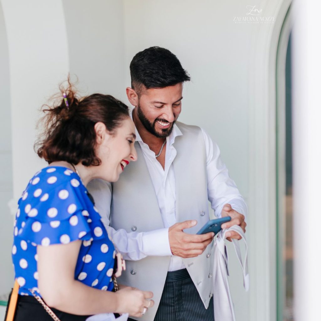lo sposo e la wedding planner che guardano il telefono